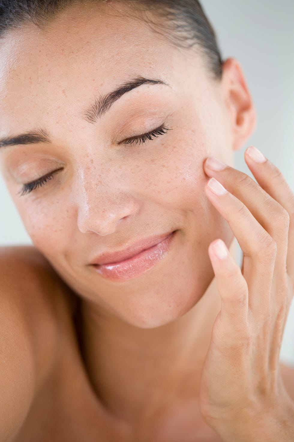 a woman with fresh skin touching her cheek