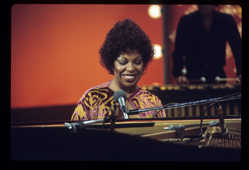 musician performing at a piano with a microphone