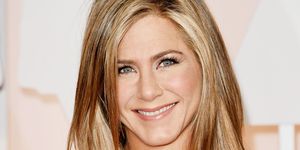 Jennifer Aniston smiles in a cream dress at the 87th Annual Academy Awards.