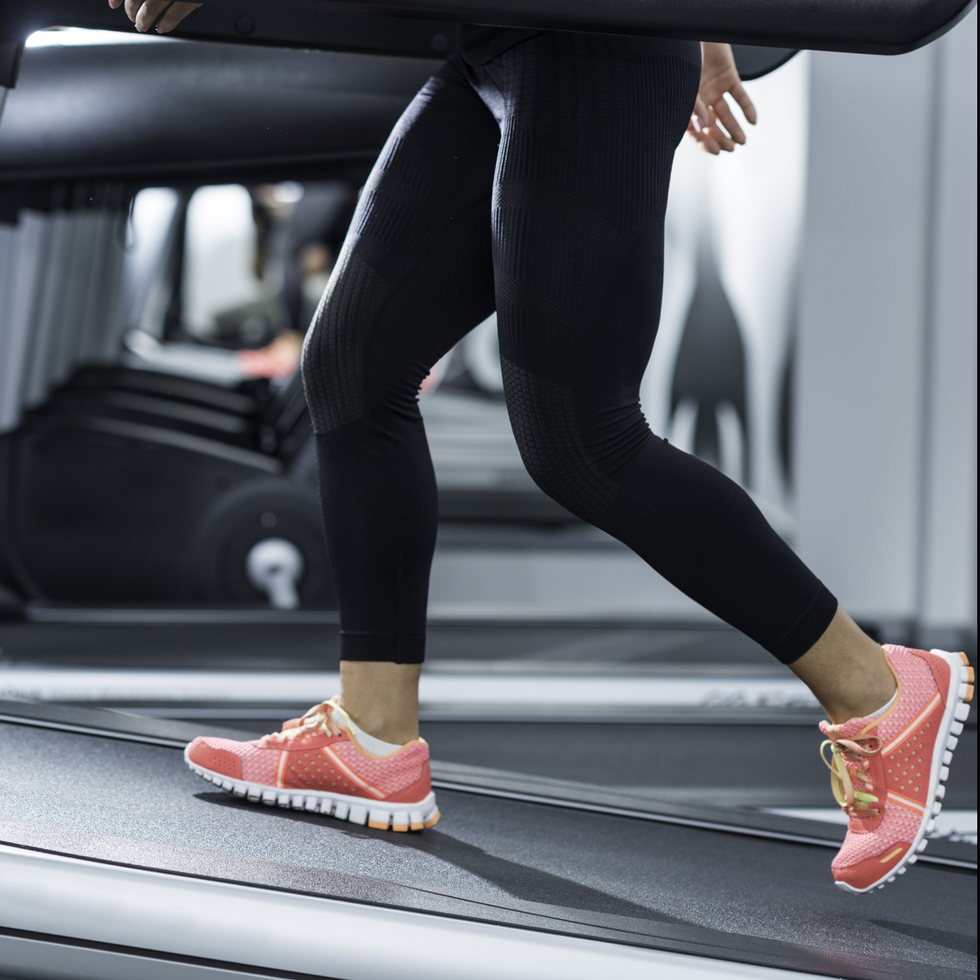 woman using incline threadmill in modern gym incline threadmills are used to simulate uphill walking or running and deliver additional workout benefits to users woman is wearing black yoga pants andrunning sports shoes