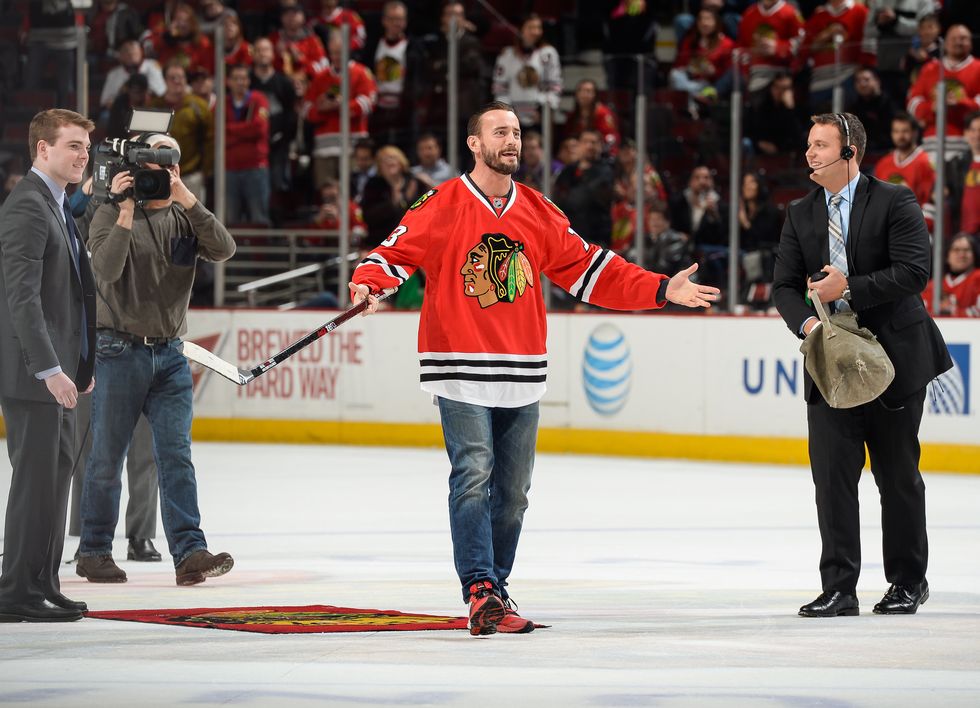 chicago, il   march 30  former wwe wrestler cm punk reacts after shooting the puck in between periods of the nhl game between the los angeles kings and the chicago blackhawks at the united center on march 30, 2015 in chicago, illinois  photo by bill smithnhli via getty images