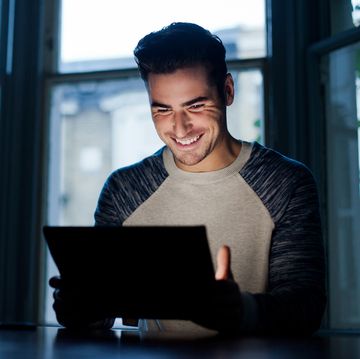 a person smiling and pointing at a laptop