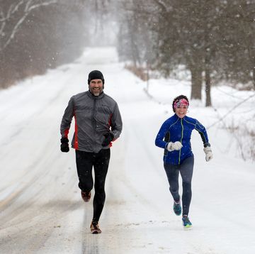 male and female running sprinting up a snowy hill during a winter training run