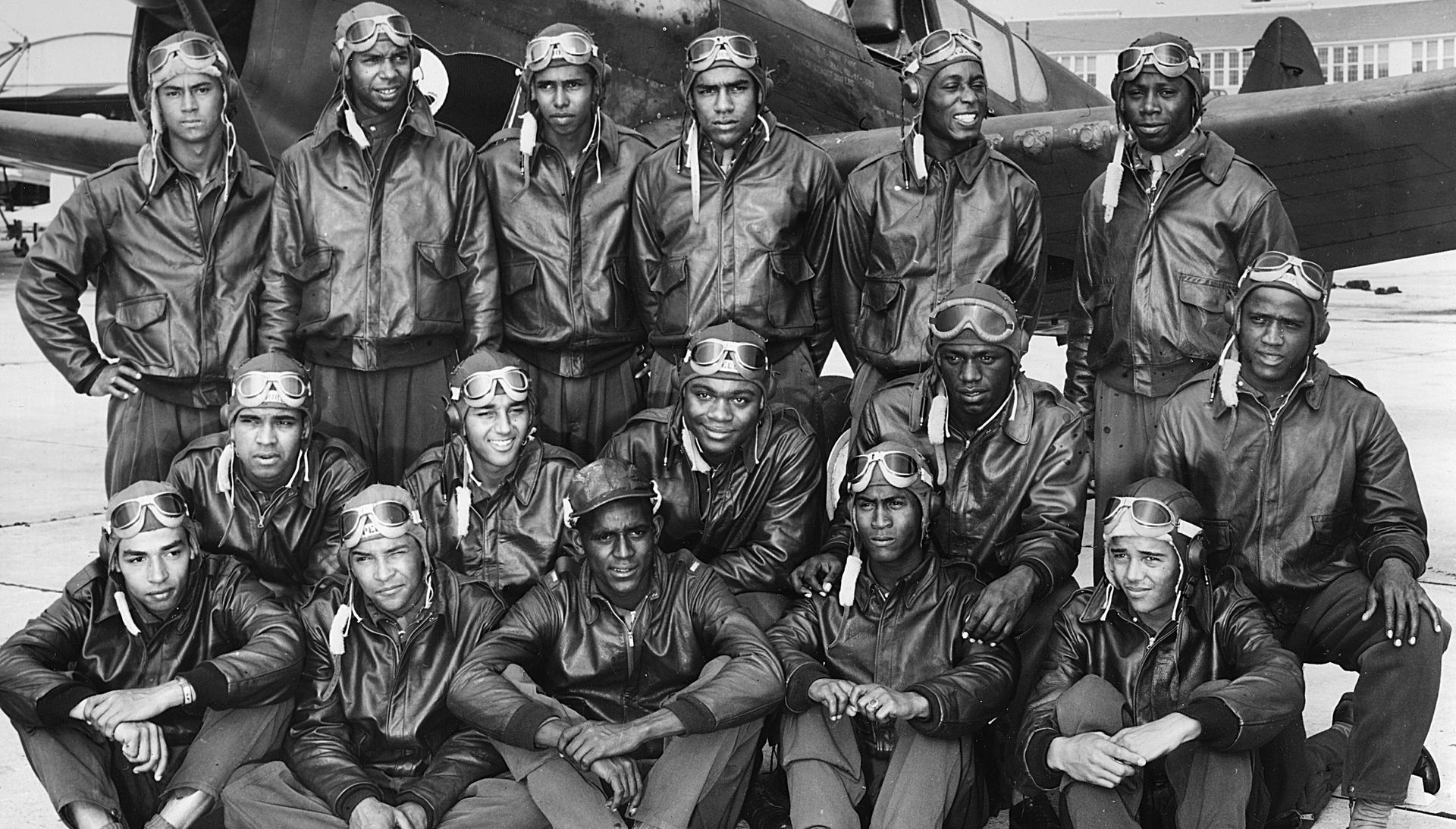 tuskegee airmen at tuskegee army flying school, in bomber jackets with a fighter airplane
