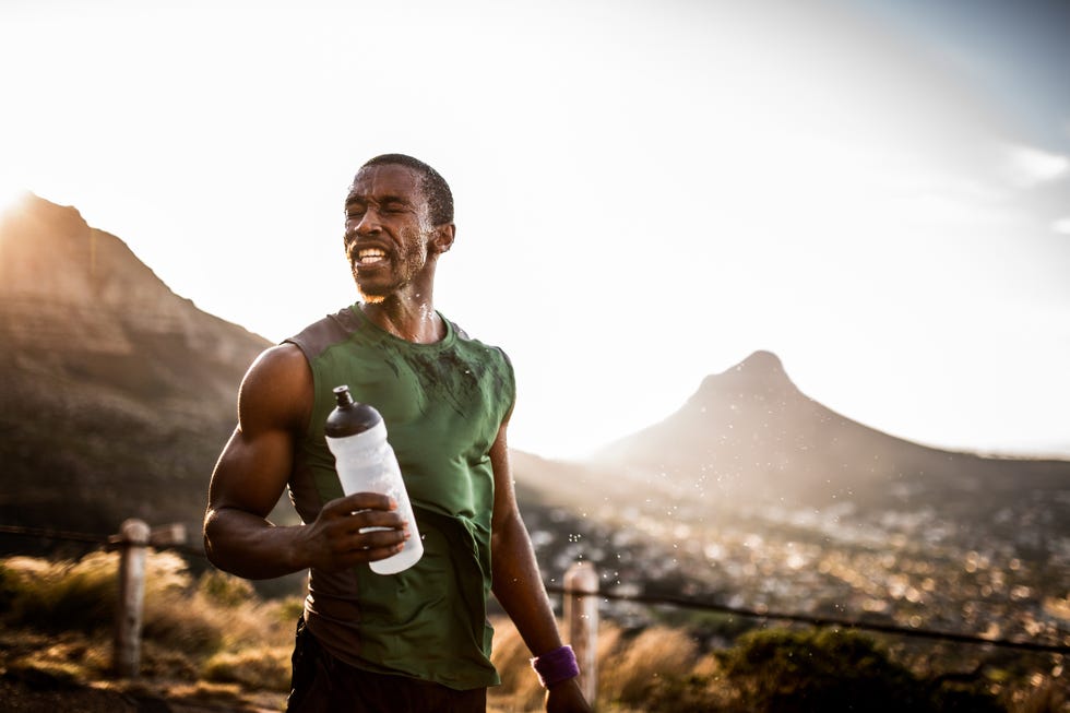 tired athlete having splashed water onto his face from his water bottle after a long run