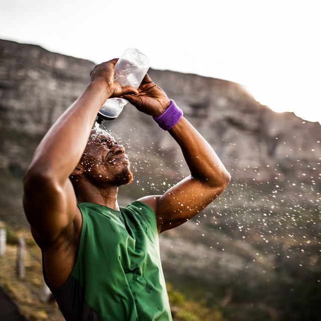 athlete splashing himself with water from his water bottle after a hard morning run