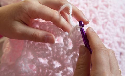 Close up of hands crocheting a pink baby blanket