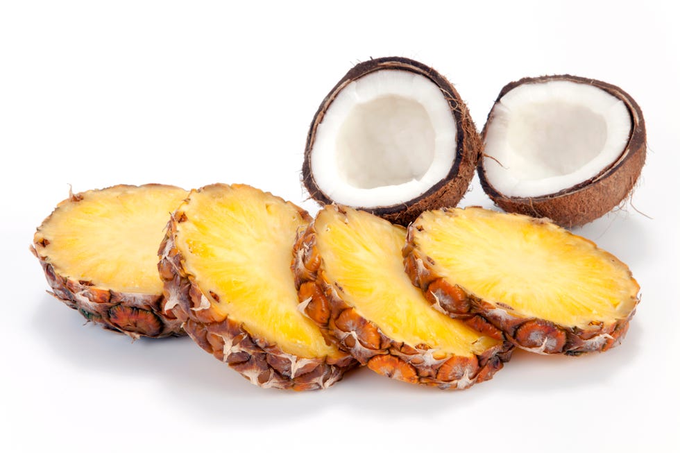 cross section of pineapple and halved coconut isolated on white background, selection focus, shallow dof