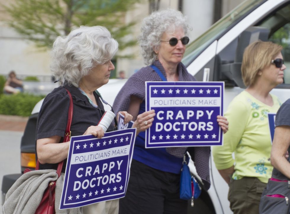 asheville, north carolina, usa may 4, 2015 older women hold signs saying politicians make crappy doctors to protest north carolinas abortion bill 465 which increases restrictions for women seeking abortions, may 4, 2015 in downtown asheville, nc