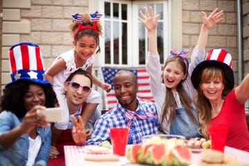 smiling friends having fun at their back yard on 4th of july taking a selfie