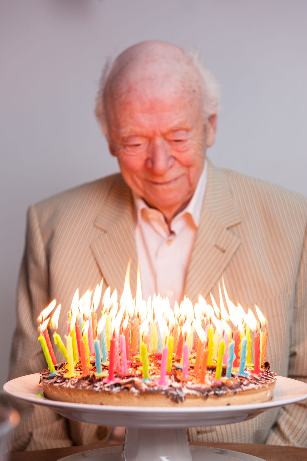 senior man looking at and enjoying his birthday cake with 93 burning candles