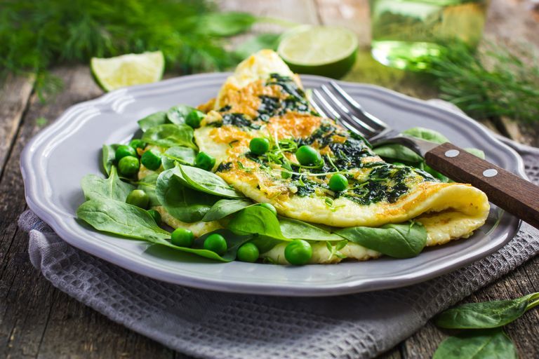 weight loss breakfast omelette with spinach and green peas on wooden background