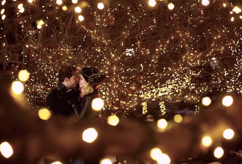 young couple kissing surrounded by city xmas lights
