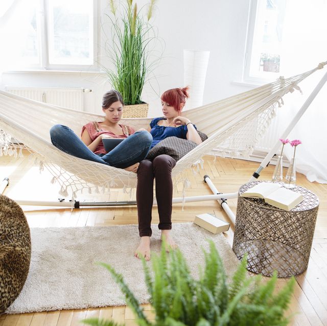 Two teenage girls relax in hammock and use tablet pc