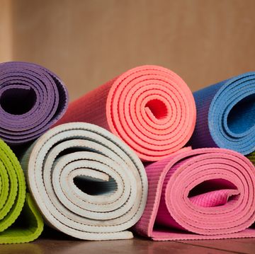 colorful yoga mats rolled up on a wooden floor in a yoga studio