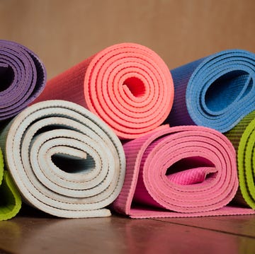 colorful yoga mats rolled up on a wooden floor in a yoga studio