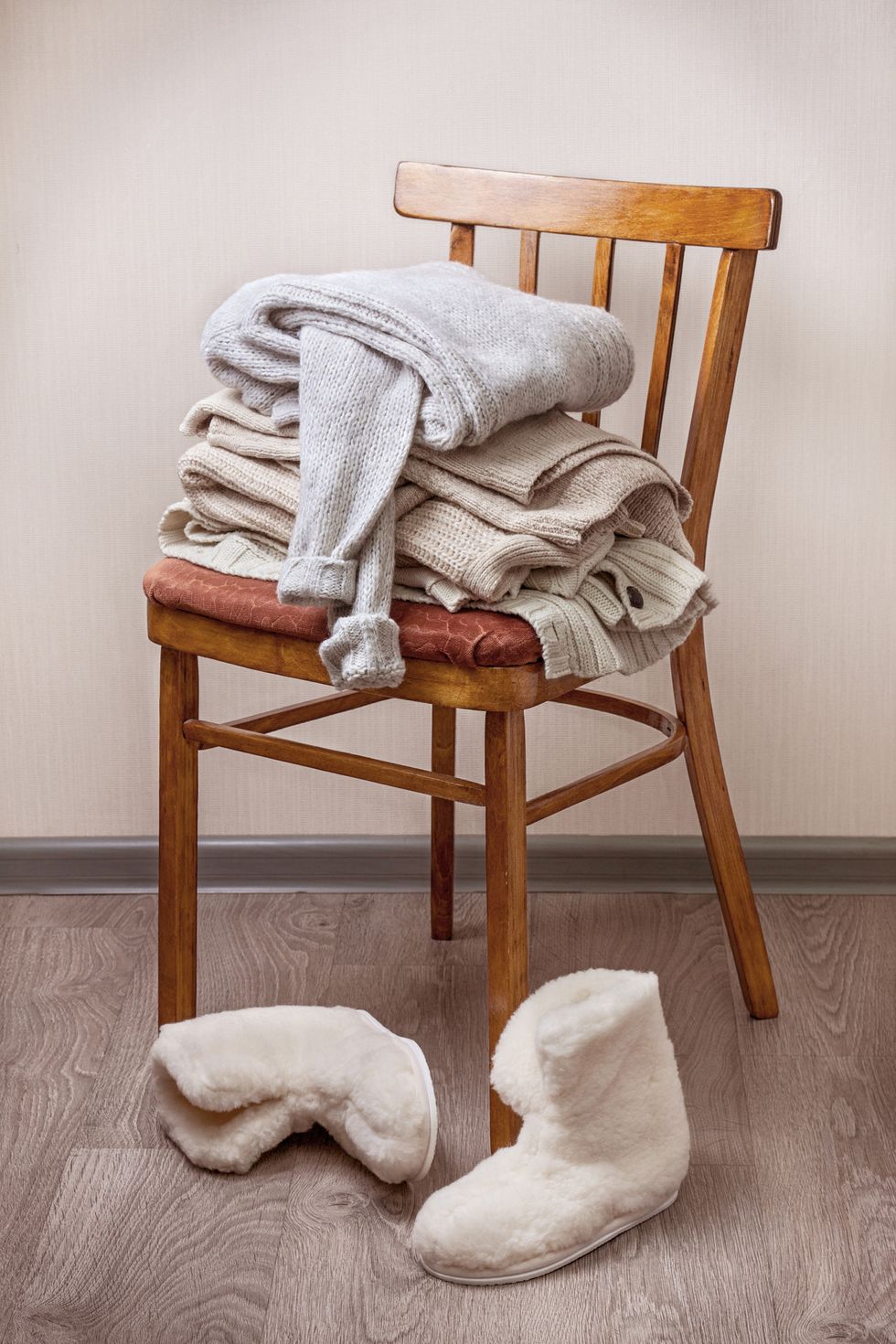 stack of warm clothes on the chair, pair of warm winter sheepskin slippers
