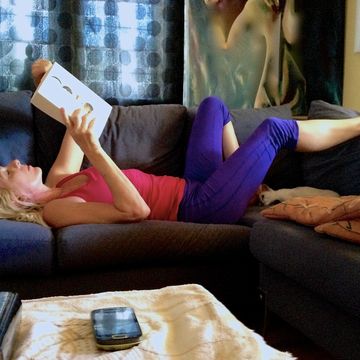 una mujer tumbada en el sofá leyendo