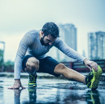 close up of a man stretching in the rain