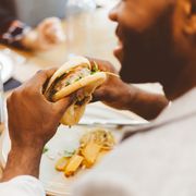 close up of afro american man eating burger in the restaurant focus on hands