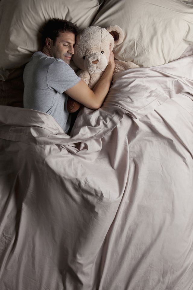 Man sleeping in bed with his teddy bear