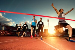 low angle view of young happy man celebrating his success after crossing the finish line and winning the race before other athletes