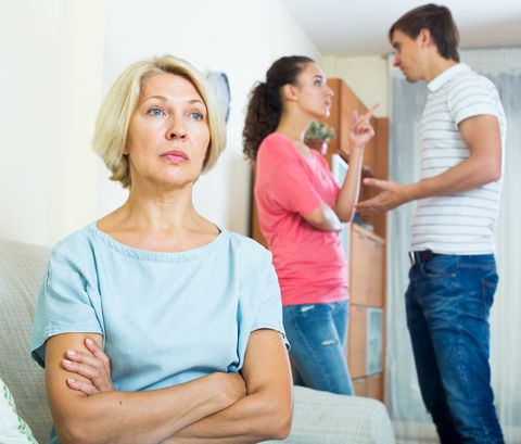 Mature woman watching young family couple quarrel at home