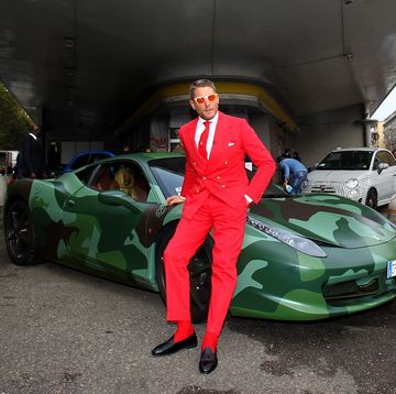 a person in a red suit standing next to a green car