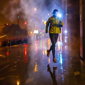 female jogger running on rainy night in the city, high iso