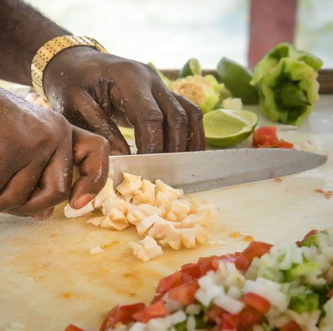 close up of hands cutting up conch for conch salad image shows other cut up ingredients such as onions, peppers and limes conch is a very popular food in the bahamas