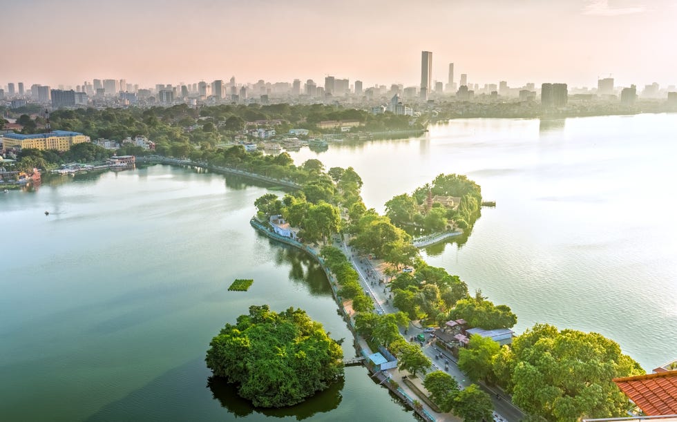 the road crossing the island westlake, hanoi, vietnam with green tree lined streets, temples located between small oasis in sunshine of west lake and boasts a beautiful evening in capital of vietnam