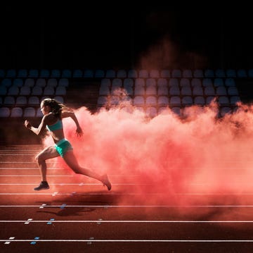 athlete running in red smoke female athlete running in red smoke on stadium