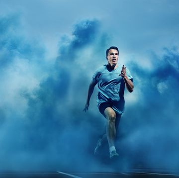 male athlete running through blue smoke