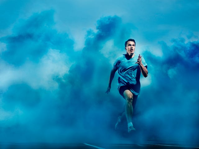 male athlete running through blue smoke