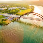 panoramic aerial view from helicopter of 360 bridge on colorado river near austin texas, looking west at sunset