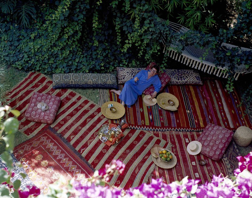 overhead shot of a designer yves saint laurent reclining in his leafy moroccan garden, strewn with rugs and pillows, wearing a blue caftan photo by horst p horstconde nast via getty images