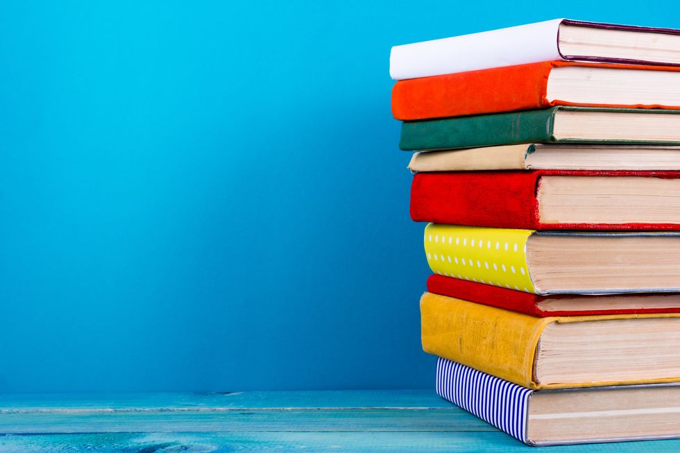 Stack of colorful hardback books, open book on blue background