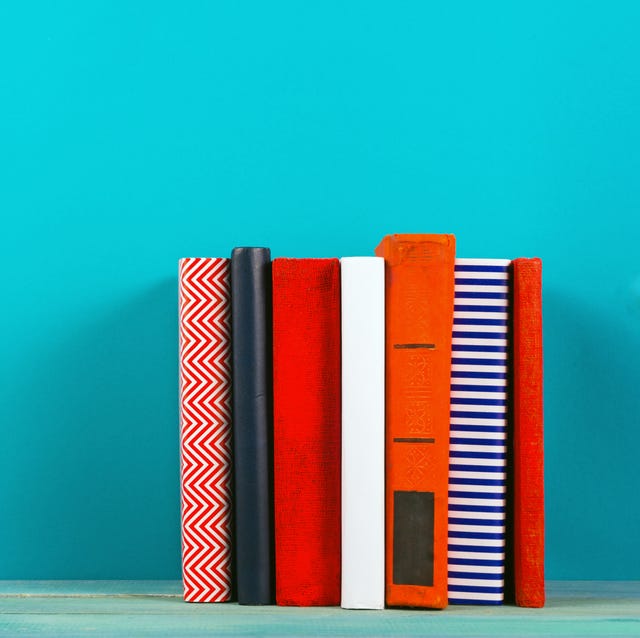 Row of colorful hardback books, open book on blue background