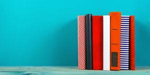Row of colorful hardback books, open book on blue background