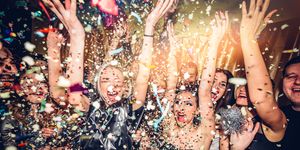 confetti falling over a smiling group of people on a dance floor of a nightclub