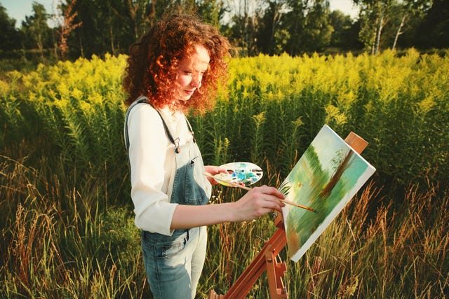 young woman painting landscape in the open air