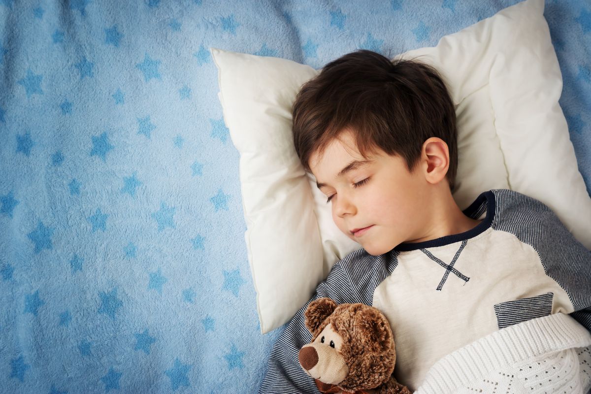 six years old child sleeping in bed with alarm clock