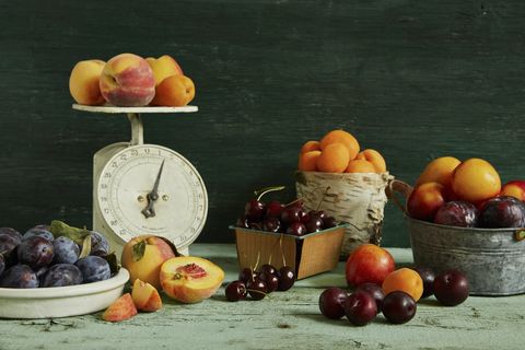 spread of various stone fruit, peaches, apricots, cherries, plums, nectarines, and prune plums on a green wood table