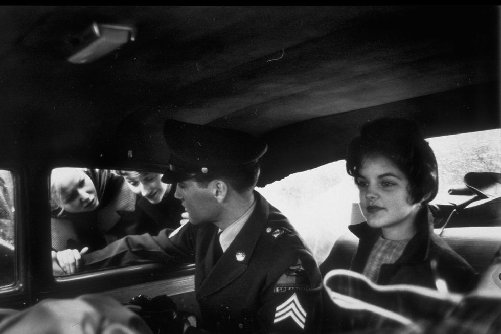 rockercorporal elvis presley wearing uniform while chatting w fans through window as girlfriend priscilla beaulieu sits beside him in back seat of car  photo by james whitmorethe life picture collection via getty images