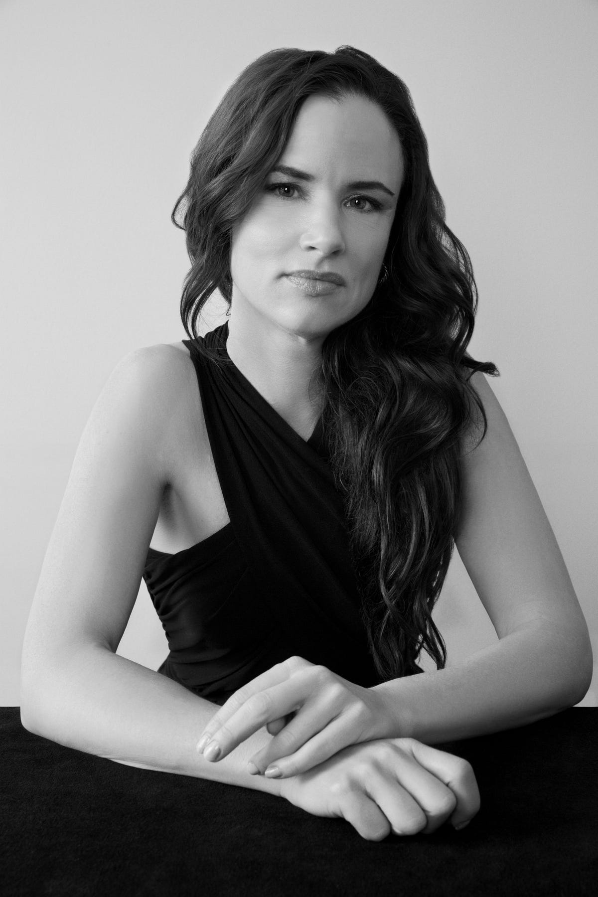 a black and white portrait of juliette lewis with her hair down wearing a black wrap neck dress