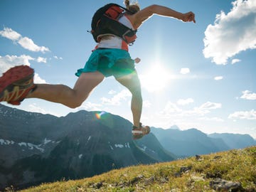 trail runner bounds along mountain ridge crest