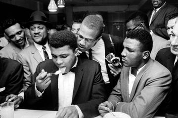 Malcolm X (C), standing behind tux-clad Muhammad Ali (L), who is surrounded by jubilant fans after he beat Sonny Liston for the heavyweight championship of the world.