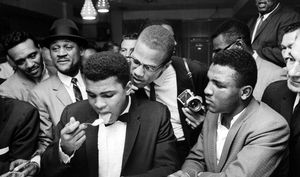 Malcolm X (C), standing behind tux-clad Muhammad Ali (L), who is surrounded by jubilant fans after he beat Sonny Liston for the heavyweight championship of the world.
