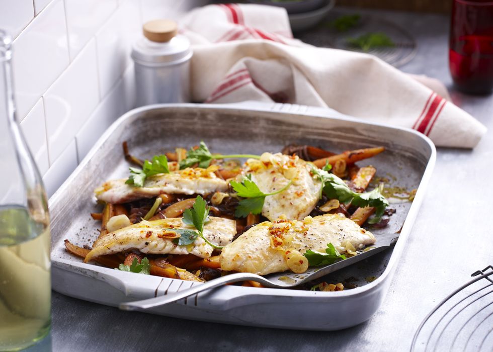 Baking tin with roast snapper with herb garnish