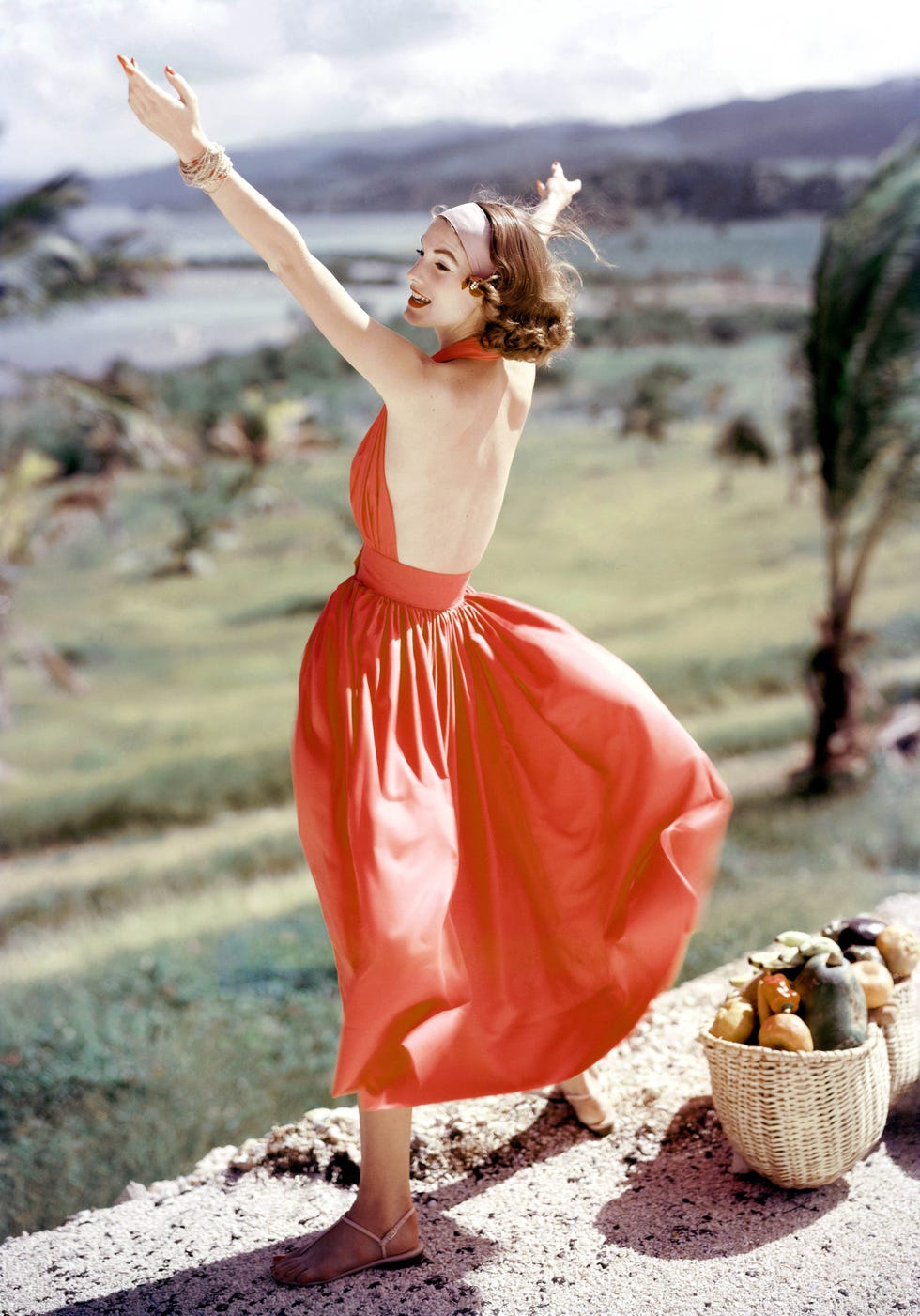 model wearing bare back sundress by claire mccardell stands on gravel ledge with arms outstreched with water in background. (photo by frances mclaughlin gill/condé nast via getty images)